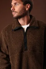 Cazadora de borreguillo color marrón, con cuello alto y cierre frontal parcial con cremallera. Presenta bolsillos laterales y diseño de manga larga.