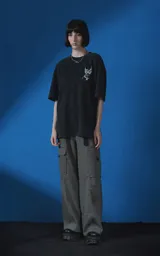 Remera de algodón premium con efecto nevado, corte oversize y cuello redondo. Presenta una estampa gráfica en color blanco en la espalda que incluye la palabra 'DESEO', una ilustración de una rosa y una figura alada, junto con frases poéticas.