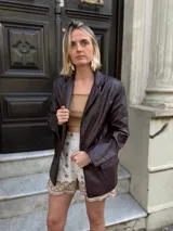 Blazer de cuero sintético en color marrón oscuro, con cierre frontal de dos botones y solapas clásicas.