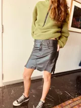 Pollera corta de cuero ovino italiano, con diseño de corte asimétrico y estilo desgastado en el ruedo. Presenta bolsillos delanteros y cierre con botón metálico.