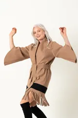 Chaquetón negro italiano con mangas irregulares, lazo y flecos en el ruedo.