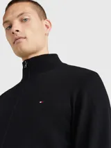 Cárdigan Tommy Hilfiger de color negro confeccionado en una mezcla de algodón pima orgánico y cachemira. Presenta un diseño con cierre de cremallera frontal, cuello levantado de punto canalé y el logo de la marca bordado en el pecho.