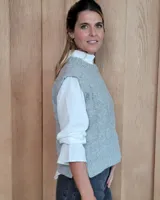 Chaleco de punto gris con diseño de trenzas y rombos en relieve, cuello redondo y terminaciones acanaladas.