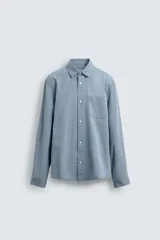 Camisa de corte relajado confeccionada en una mezcla de lyocell y algodón con efecto lavado. Presenta cuello solapa, manga larga con puños abotonados, bolsillo de plastrón en el pecho y cierre frontal con botones.