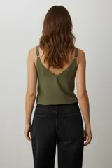 Top de viscosa ajustado al cuerpo, con escote profundo en V y detalle de argolla metálica en el centro del busto. Presenta un estampado geométrico en tonos verde oliva y beige claro.