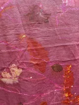 Mantel rectangular de lino color rosa con estampado de hojas y flores en tonos naranja, marrón y blanco.