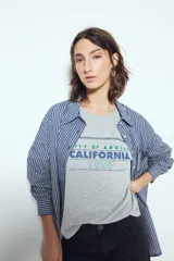 Remera negra de manga corta con estampado tipográfico "City of Angels California 1997" en tonos marrones y costuras visibles en blanco.