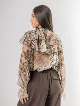 Camisa de seda italiana con diseño reversible, permitiendo usar el lazo en la parte frontal o posterior. Presenta un estampado sutil con motivos abstractos y animal print, cuello alto con volados, mangas largas con puños elásticos y corte holgado.
