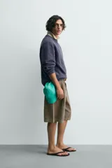 Jersey de hombre de corte relajado, color azul oscuro o morado apagado, con textura rizada (bouclé) y cuello redondo.