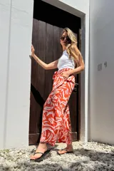 Pantalón amplio color naranja con estampado abstracto en blanco, cintura elastizada y bolsillos laterales.