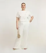 Pantalón de vestir blanco, modelo flare con corte sastrero, bolsillos laterales y elástico en la espalda.