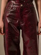 Pantalon de corte recto con diseño de estampado de piel de serpiente, confeccionado en cuero sintético (PU). Presenta bolsillos laterales y cierre frontal con botón.