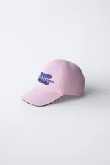 Gorra de béisbol azul marino con visera curva y detalle de borde en color crema. Presenta un bordado frontal con la palabra 'LONDON' en tipografía estilo varsity y texto adicional debajo.