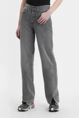 Jean de corte baggy y tiro medio, con diseño de costuras retorcidas y abertura en el ruedo. Presenta cierre de botones a la vista y un acabado lavado en tono gris.