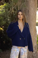 Saco de punto acanalado en color azul marino, con diseño cruzado, cierre de doble botonadura y mangas largas holgadas.