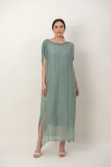 Vestido largo de seda color verde seco, con transparencias en el ruedo, mangas cortas y detalle de guarda bordada con lentejuelas en hombros y mangas.