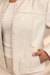 Campera de cuero negro con detalles de costuras decorativas en los bordes delanteros y mangas largas.
