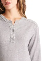Buzo de tejido fino con escote henley y cierre de botones. Presenta detalles acanalados en hombros, puños y ruedo, con una silueta cómoda y terminación redondeada en la parte inferior.