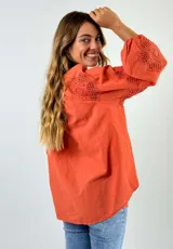 Blusa blanca de algodón con cuello mao y mangas 3/4 con detalles de encaje calado.