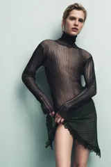 Top semitransparente de punto fino color negro, con cuello subido y manga larga.