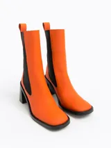 Botín de piel negra, estilo Chelsea, con elásticos laterales y punta cuadrada. Presenta un tacón ancho y alto.