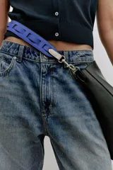 Bolso de hombro formato saca de color negro, con cierre mediante clip metálico y un compartimento interior extraíble con cremallera. Incluye un asa de hombro con diseño estampado y detalles metálicos dorados.
