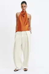 Top de cuello halter satinado en color naranja tostado, con espalda descubierta y cierre trasero de botones.
