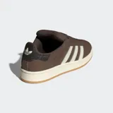 Championes Adidas Campus 00s de color marrón, confeccionados en cuero con las icónicas tres tiras dentadas en color blanco. Presentan una suela de caucho en tono crema y detalles en dorado, con un diseño inspirado en la cultura urbana y el skate de los años 2000.
