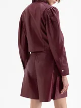 Short de cuero color vino tinto con tablas que generan volumen en las piernas, cintura doble con pespunte y botones forrados en cuero. Cierre lateral.