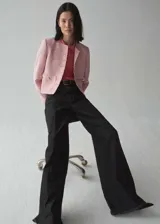 Chaqueta de tweed en tonos rosados, con cuello redondo, manga larga y cierre frontal con botones metálicos. Presenta dos bolsillos de parche en la parte delantera y diseño entallado con forro interior.