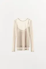 Camiseta de manga larga color beige, con cuello redondo y detalle de camiseta interior en el mismo tejido. Tiene un bajo asimétrico y corte slim fit.