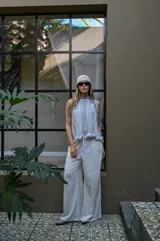 Pantalón de corte amplio y tiro alto, confeccionado en tela negra con acabado brillante y sutil efecto glitter. Presenta cintura elástica con cordón ajustable y caída fluida.