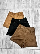 Short de gamuza con diseño de tiro alto, cierre frontal con botón y detalle de tachas metálicas en los bolsillos delanteros y en el ruedo.