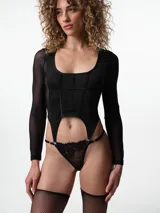 Top de manga larga con diseño tipo corset, confeccionado en tela negra con paneles de tul transparente en los laterales y mangas. Presenta escote redondo y tiras elásticas inferiores con ganchos de portaligas.