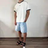 Remera de corte regular color blanco con detalles en gris oscuro en el cuello y los bordes de las mangas. Presenta un estampado pequeño centrado en el pecho.