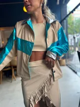 Camisa color beige con detalles en azul metalizado en mangas y pecho, y plateado en cuello y puños.