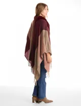 Ruana tejida con diseño de bloques de color en tonos tierra y bordó, con cuello de piel sintética en color bordó y terminación de ruedo con flecos.