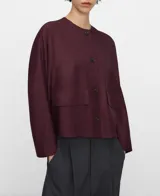 Camisa corta bordó de línea recta, con escote redondo a la base, manga japonesa y cierre frontal con botones. Cuenta con bolsillos delanteros de plastrón con solapa.