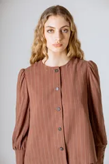 Chaqueta marrón a rayas verticales, con cuello redondo, cierre frontal con botones y mangas largas abullonadas con puños abotonados.