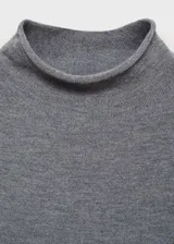 Buzo de punto fino en color gris, con cuello perkins y manga larga. Presenta un diseño recto y entallado al cuerpo.