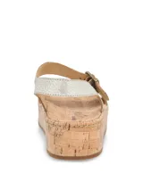 Sandalias Hush Puppies modelo Zug, de color plateado, con plataforma de corcho y capellada de cuero. Cuentan con tira en el antepié y tira trasera con hebilla metálica de ajuste.