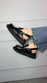 Zuecos cerrados tipo sandalias de plataforma, confeccionados en cuero con efecto craquelado en tono azul, con tiras texturizadas, argollas metálicas decorativas y tira trasera con hebilla regulable.