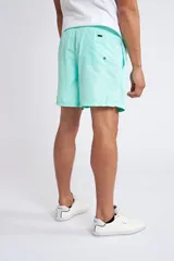 Short de baño color turquesa con cintura elástica y cordón ajustable. Presenta bolsillos laterales y un bolsillo trasero, con el logo de la marca bordado en la parte inferior de la pierna.