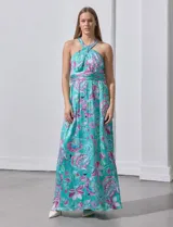 Vestido largo de gasa con estampado floral en tonos turquesa, rosa y verde. Tiene cuello halter cruzado, corte en la cintura con faja plisada y abertura en la espalda con cierre invisible.