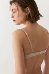 Soutien push-up color beige en punto acanalado, con copas acolchadas, aros, breteles ajustables y cierre de corchetes en la espalda. Presenta detalles de encaje en la parte superior de las copas y un pequeño lazo en el centro.