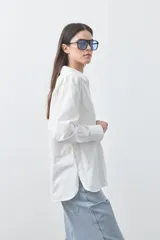 Camisa de manga larga de algodón en color blanco, con cuello clásico, cierre frontal de botones y silueta relajada.