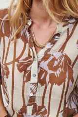 Camisa de manga larga con estampado floral en tonos marrones y negros, cuello mao y cierre frontal parcial con botones.