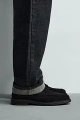 Mocasín de vestir para hombre, confeccionado en piel con acabado serraje (gamuza), color negro. Presenta un detalle de antifaz en el empeine y suela negra a contraste con un ligero tacón.