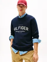 Buzo de algodón orgánico color azul marino con cuello redondo y terminaciones acanaladas. Presenta un gran logo gráfico de Tommy Hilfiger con el texto "Heritage & Excellence" y la inscripción romana "MCMLXXXV" en blanco en el frente.