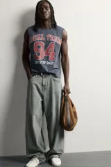 Musculosa gris oscuro de ajuste relaxed, con cuello redondo y diseño sin mangas con sisa amplia. En el frente presenta una estampa estilo varsity en tonos bordó y blanco con la inscripción "Local Team 94 One Step Daily".